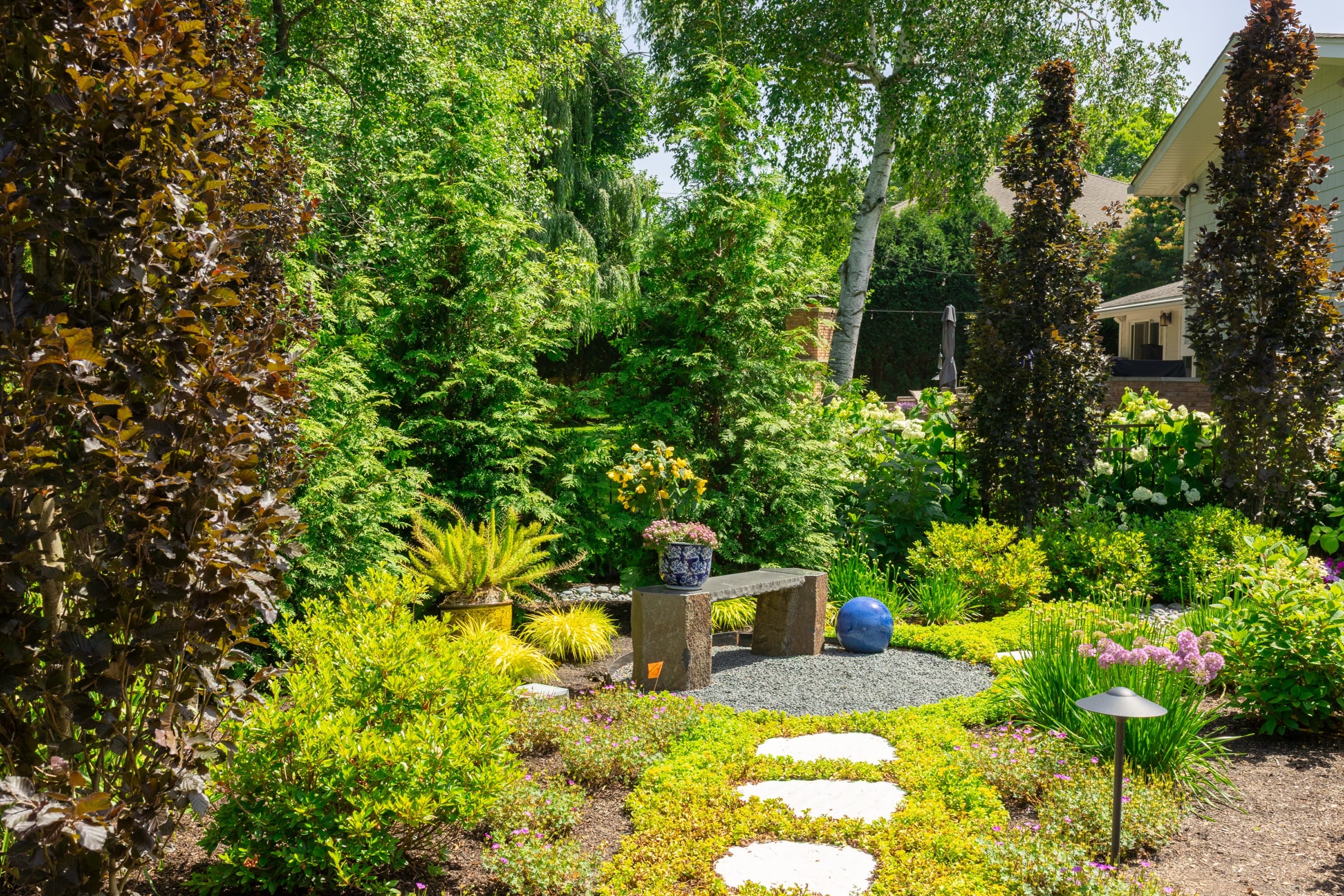 A secluded garden bench framed by layered perennials and stepping stones
